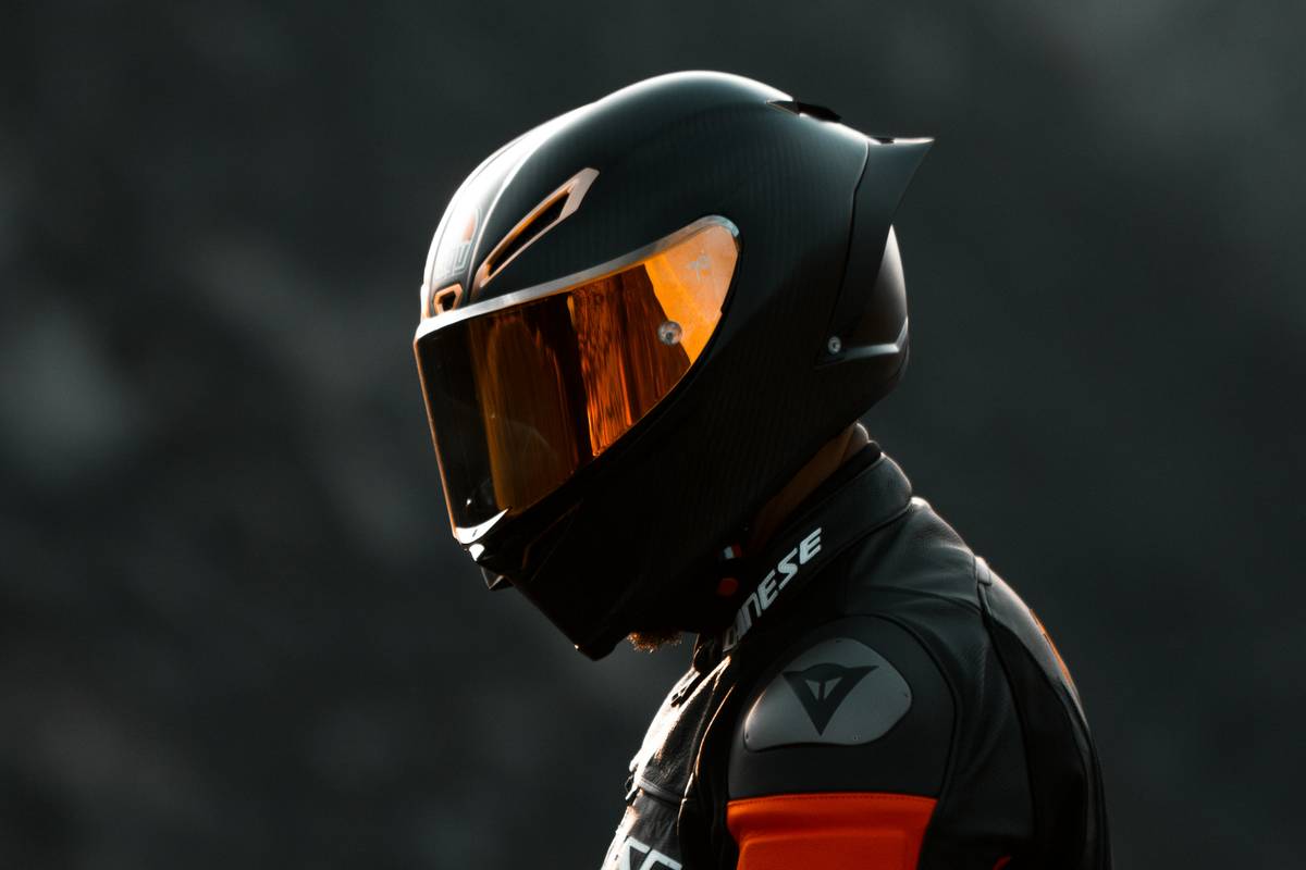 Motorcycle rider dressed in black leather race suit modeling for a side profile shot.